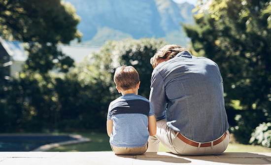 father and young son sitting on steps outside and talking