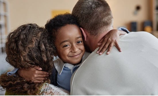 Young boy hugging his mom and dad at the same time
