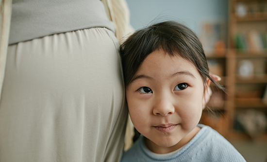 small child with ear against pregnant mom's belly