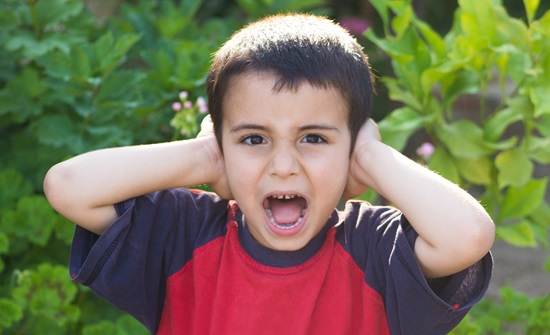 Young boy covering his ears with his hands
