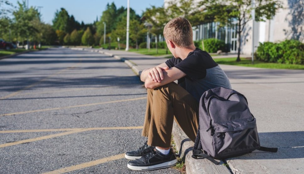 young boy sitting alone on a curb