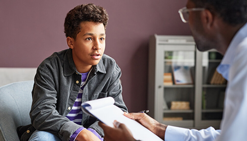 teen boy speaking with therapist in office