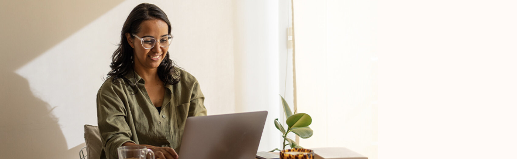A smiling woman types on her laptop.