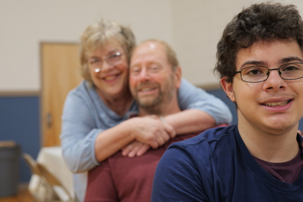 A young man with two adults behind him.