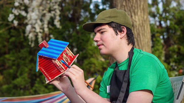 Teenager with autism outside doing a painting craft
