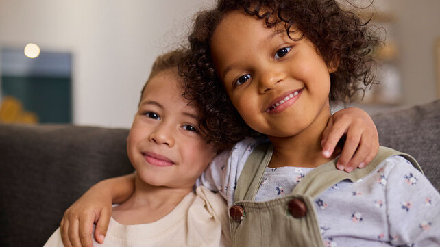 Young siblings with arms over each others shoulders